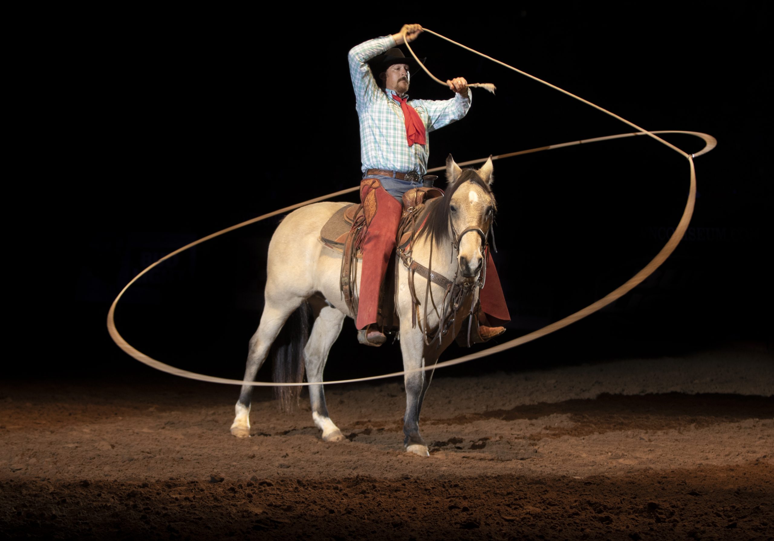 Photograph of a cowboy trick roper on a horse.