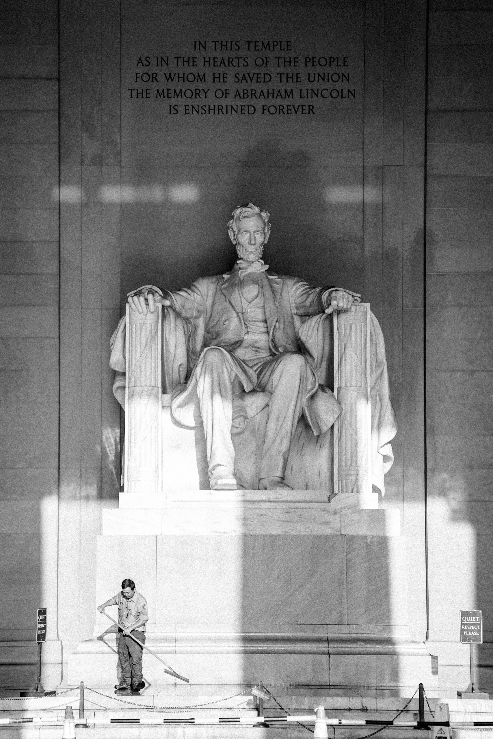 A photo of the Lincoln memorial with a cleaning worker at the base