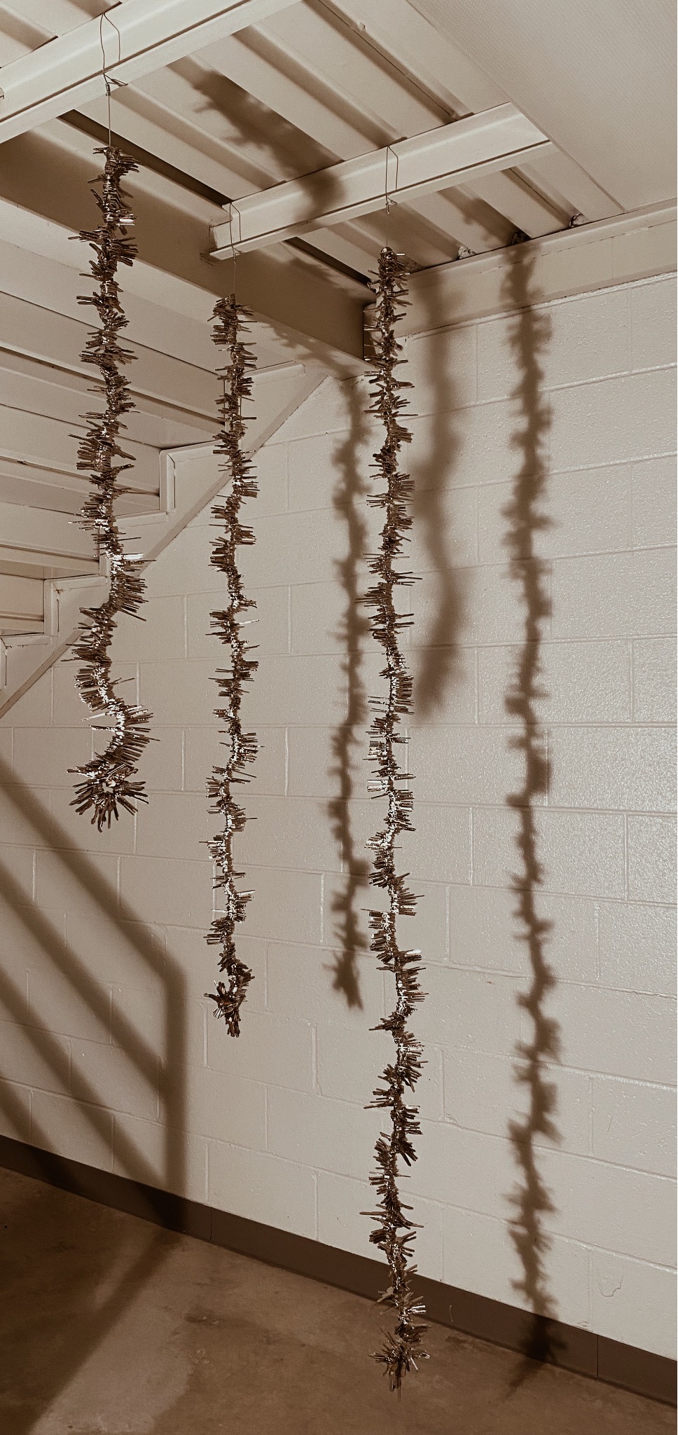 Three sets of wires with keys hung on them, hanging from a staircase.