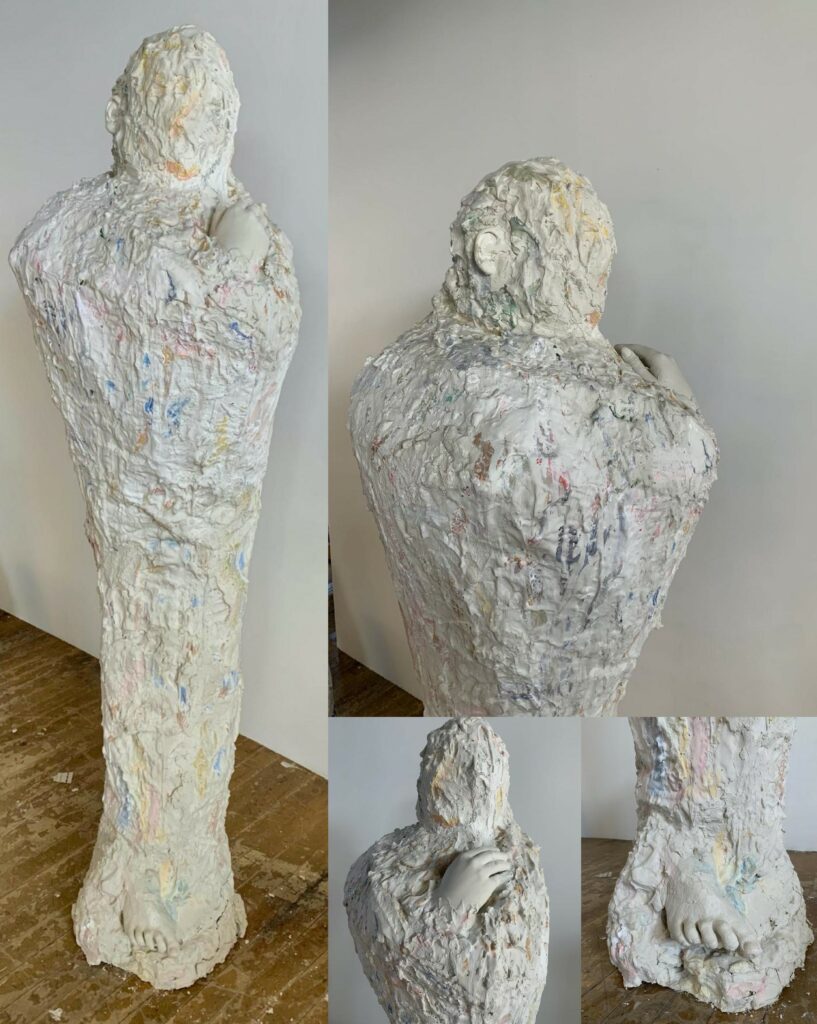 Mottled white sculpture of a human-like figure.